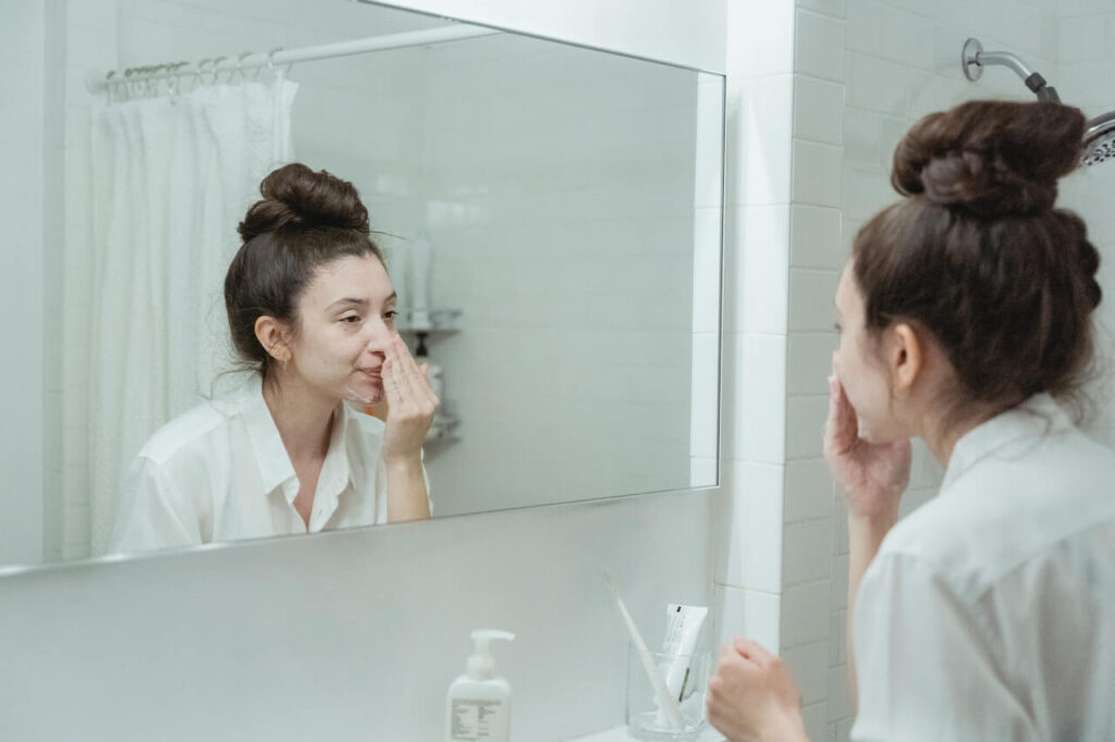 Washing Your Face - Woman looks into mirror cleaning her face